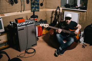 Obraz premium Guitarist in old garage music studio. Messy basement with instruments, album recording process