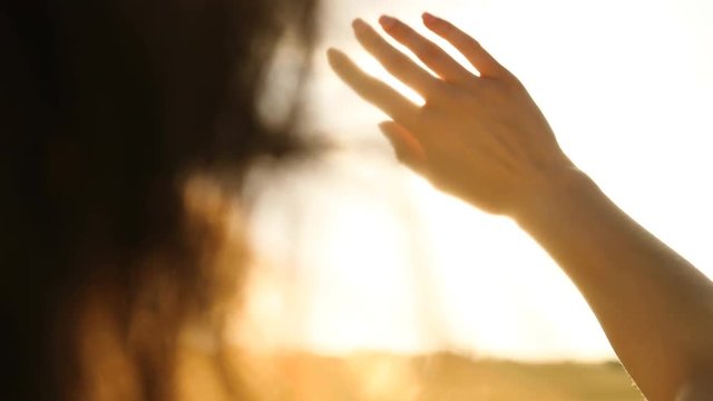 Close up shot of woman hands putting throught the sun light on the sky background. Slow motion.