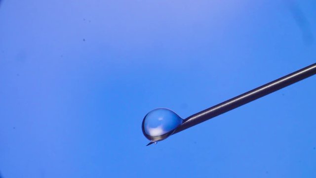 Water drop falling from the syringe needle