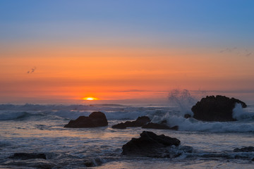 Fototapeta premium Atardecer con ola impactando en una roca.