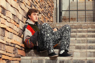 Sad young fashion hippie man sitting on the steps