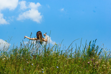 girl in a dress in a field among flowers and herbs