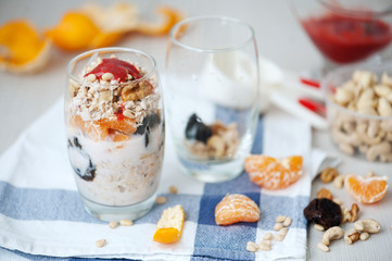 Yogurt oat granola with berries, mandarin and nuts in glass jars