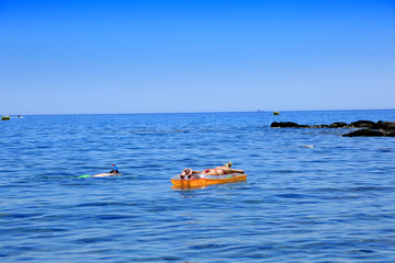 Młoda kobieta na pontonie i mężczyzna nurkuje w wodzie morza Śródziemnego. - obrazy, fototapety, plakaty