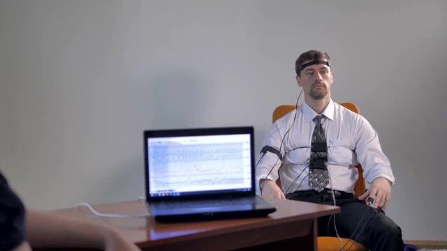 A businessman sits for a lie detector examination. 