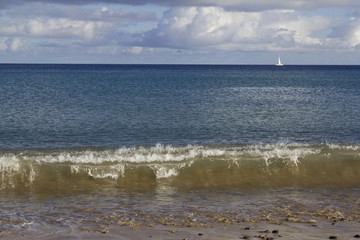 Fototapeta na wymiar Mar azul com pequeno veleiro ao longe