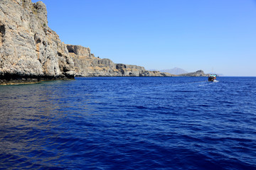 Piękne skaliste wybrzeże wyspy Rodos w Grecji, statek z turystami.