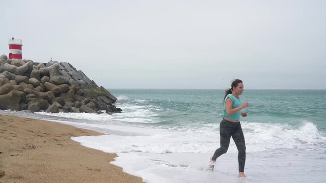 Athletic woman running along the beach. Slow motion