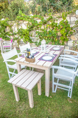 Decorated wooden table with candles and silverwear in open garden