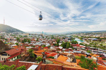 Fototapeta na wymiar Panorama view of Tbilisi, capital of Georgia country. View from Narikala fortress. Cable road above tiled roofs.