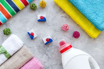 Housework. Wash clothes. Dry and liquid detergents near clean towel on grey stone background top view