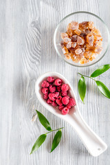 Making raspberry jam. Berries and sugar on grey wooden background top view copyspace