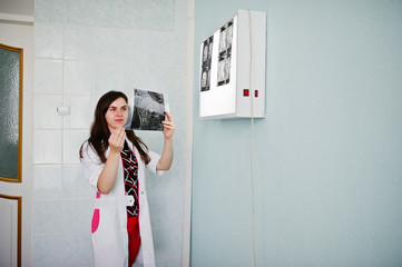 Portrait of a doctor looking at x-ray image of her patient's body part.