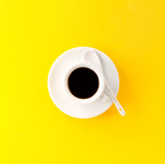 Coffee espresso in small white ceramic cup on yellow vibrant background. Minimalism Food Morning Energy Concept.