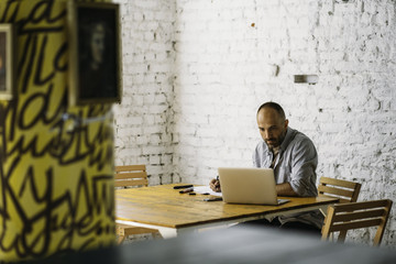 Senior designer working at laptop and sketches