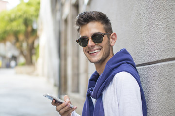 portrait of young teenage man with mobile phone on the street