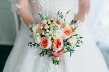 Beautiful bridal bouquet with white roses and peach peonies in a bride hands in white dress. Wedding morning. Close-up - 166499492