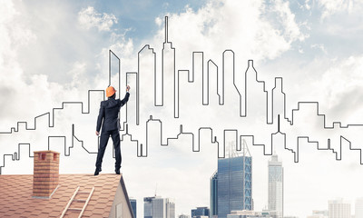 Man architect draw silhouette of modern city on blue sky. Mixed 