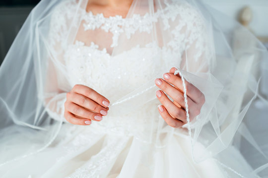 Close-up image hands of the charming bride with a veil. Wedding preparation