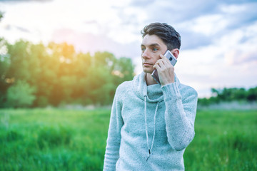 Fototapeta premium Young man businessman talking at mobile phone outside on a grass field