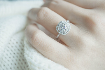 Close up Diamond ring on woman's finger before wedding with white scarf background.(soft and selective focus)