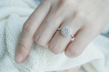 Close up Diamond ring on woman's finger before wedding with white scarf background.(soft and...
