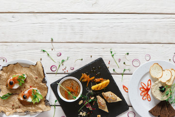 Various appetizers on free wood space. Snacks before dinner, decorated with sliced red onion, herbs and aromatic spices on desk