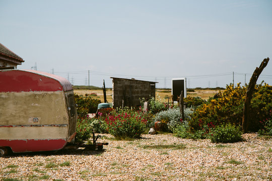 A shingle garden with a vintage, run-down, caravan.