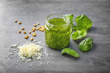Delicious sauce in jar with ingredients on grunge background