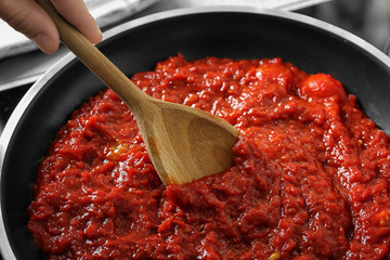 Woman preparing tomato sauce in frying pan