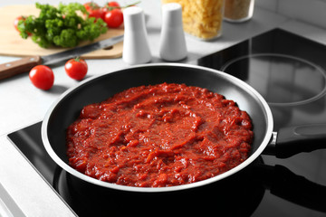 Frying pan with tomato sauce on electric stove