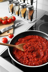 Frying pan with tomato sauce on electric stove