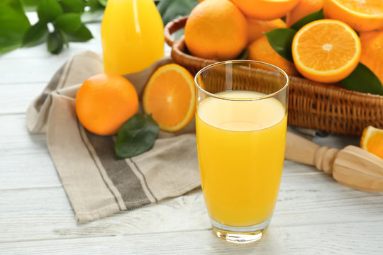 Glass of fresh orange juice with fruit on wooden background