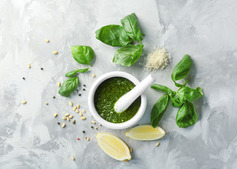 Delicious sauce in mortar with pestle and ingredients on grey background