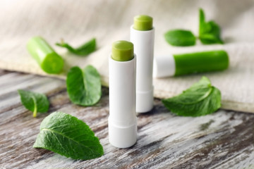 Hygienic lipsticks with lemon balm on wooden table
