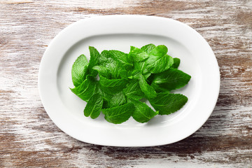 Plate with leaves of lemon balm on table