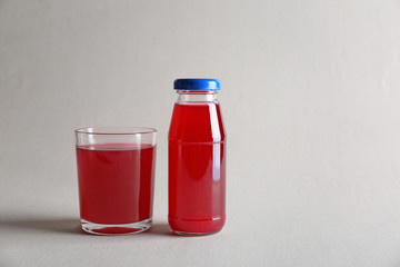 Bottle and glass with delicious juice on light background