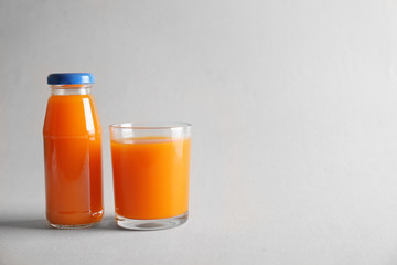 Bottle and glass with delicious juice on light background