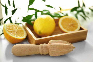 Wooden juicer and box with lemons on white background