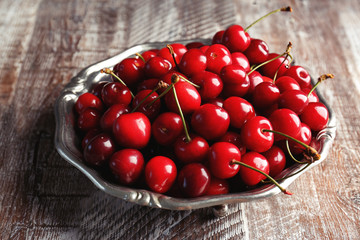 Plate with sweet cherries on wooden background