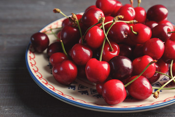 Plate with sweet cherries on wooden background, closeup