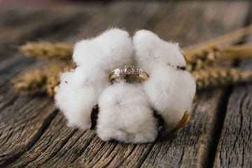 Engagement ring in cotton flower on wooden background. Natural. Wedding in rustic style