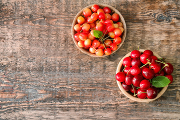 Two bowls with fresh ripe cherries on wooden background