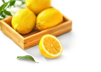 Wooden box with lemons on white background