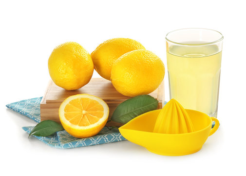 Composition with lemons, squeezer and glass of juice on white background