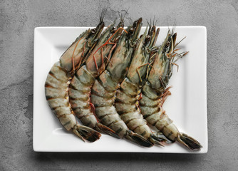 Plate with fresh shrimps on grey background