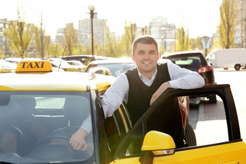 Handsome taxi driver standing near car with opened door on street