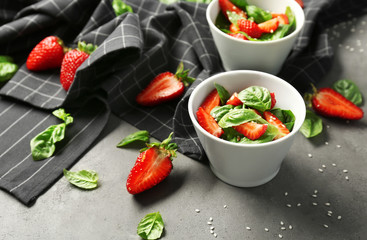 Bowls with tasty strawberry spinach salad on table