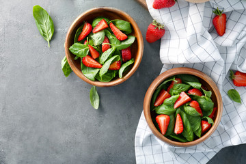 Bowls with tasty strawberry spinach salad on table