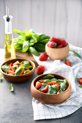 Bowls with tasty strawberry spinach salad on table